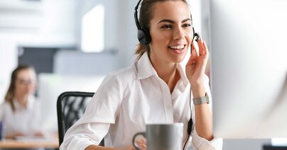 Clerk in an office call center working on the computer with headphones.