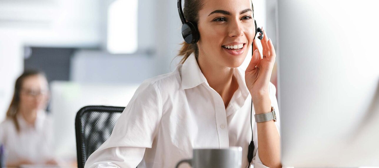 Sachbearbeiterin in einem Büro-Callcenter, die mit Kopfhörern am Computer arbeitet.